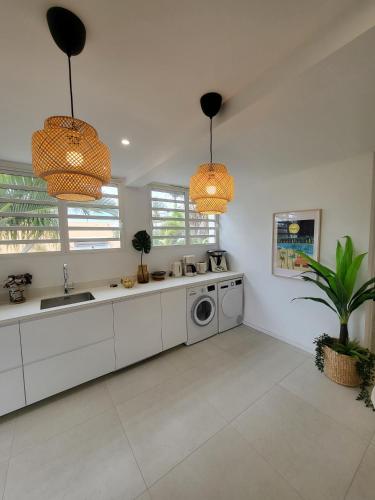 a kitchen with white cabinets and a washing machine at Les Hauteurs de la Baie in Noumea