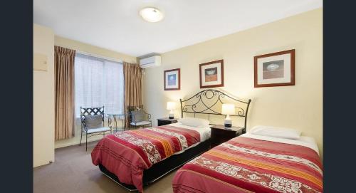 Knightsbridge Apartments في ملبورن: غرفة فندقية بسريرين وطاولة