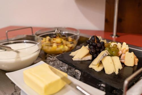 a cutting board with cheese and grapes and other foods at Hotel Staribacher Südsteiermark in Leibnitz