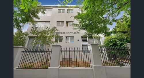 Un edificio blanco con una valla delante. en Knightsbridge Apartments, en Melbourne