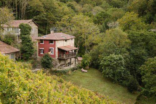 a large red house in the middle of a forest at Casa Muíñovedro in Chantada