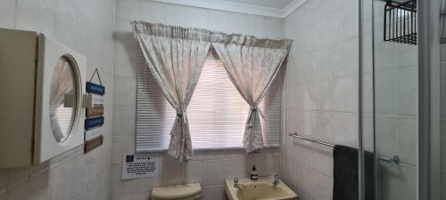 a bathroom with a sink and a toilet and a window at Tenuta Overnight in Polokwane