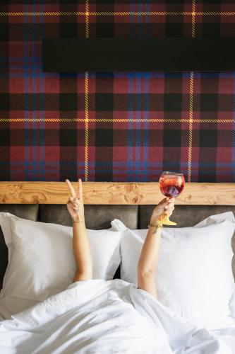 a person laying in bed holding a glass of wine at Mamie Megève in Megève