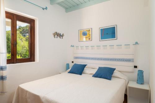 ポルト・ロトンドにあるVilla Petraの白いベッドルーム(青い枕のベッド付)