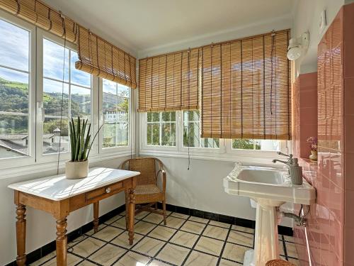 a bathroom with a sink and a table and windows at ETXEALE in Valcarlos