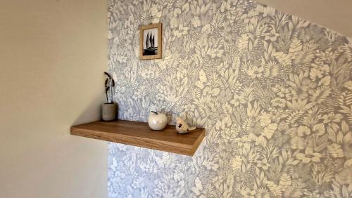 a wall with a blue and white wallpaper with two vases on a shelf at Entre Alpes et Léman in Publier