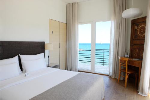 a bedroom with a bed and a balcony with the ocean at Hostal Empúries in L'Escala