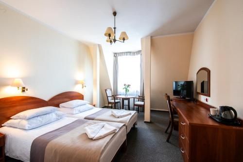a hotel room with two beds and a television at Rewita Międzyzdroje - Grunwald in Międzyzdroje