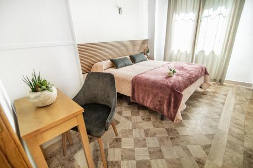 a bedroom with a bed and a table and a chair at Hotel Reina Mora in Granada