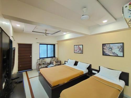 Habitación con 2 camas y TV. en HOTEL PANETAR PALACE, en Ahmedabad