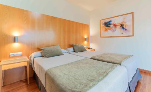 a hotel room with two beds and a table at Checkin Camino de Granada in Granada