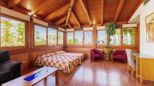 - une chambre avec un lit et des chaises dans une pièce dotée de fenêtres dans l'établissement Checkin Camino de Granada, à Grenade