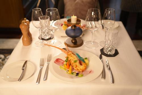 a white table with a plate of food on it at Paradise Elegance Cruise Halong in Ha Long