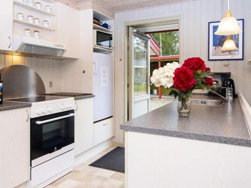 a kitchen with a vase of flowers on a counter at 4 person holiday home in F rvang in Fårvang