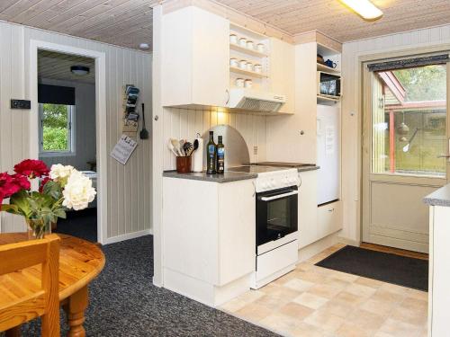 una cocina con armarios blancos y una mesa con un jarrón de flores en 4 person holiday home in F rvang, en Fårvang