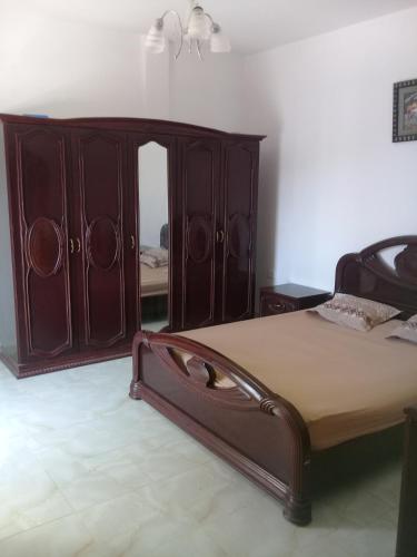 a bedroom with a bed and a wooden cabinet at Maison a louer a la grotte de Bizerte in Dar el Koudia