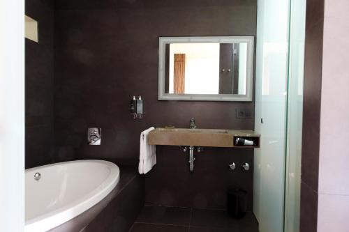 a bathroom with a sink and a tub and a mirror at Hostal Empúries in L'Escala