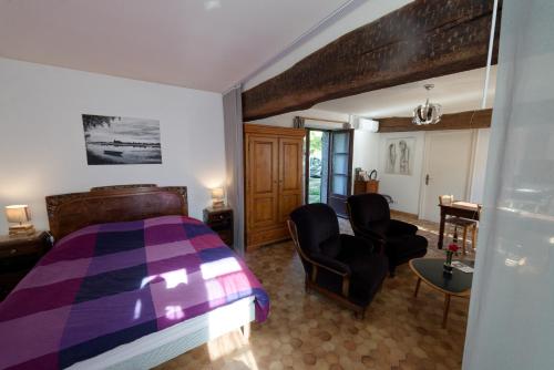 Saint-Dyé-sur-LoireにあるLa Boisseléeのベッドルーム(紫色のベッド1台、椅子2脚付)