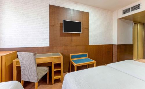 a hotel room with a bed and a desk and a tv at Checkin Camino de Granada in Granada