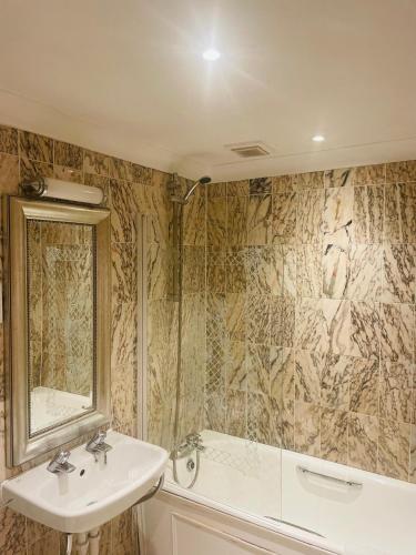 a bathroom with a sink and a mirror and a tub at The Colonnade in London