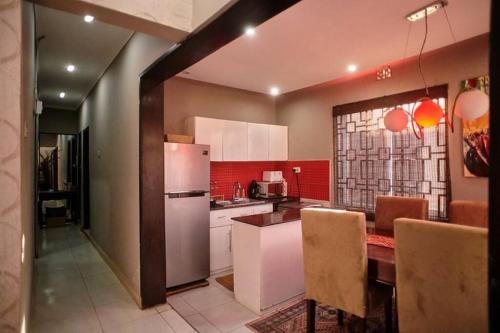 a kitchen with a refrigerator and a table with chairs at The Hatua Peaceful Homeaway Haven in Arusha