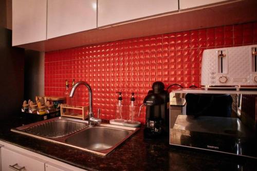 uma cozinha com um lavatório e uma parede vermelha em The Hatua Peaceful Homeaway Haven em Arusha