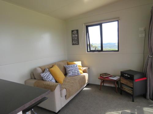 a living room with a couch and a window at Tuis Scenic Retreat in Cable Bay
