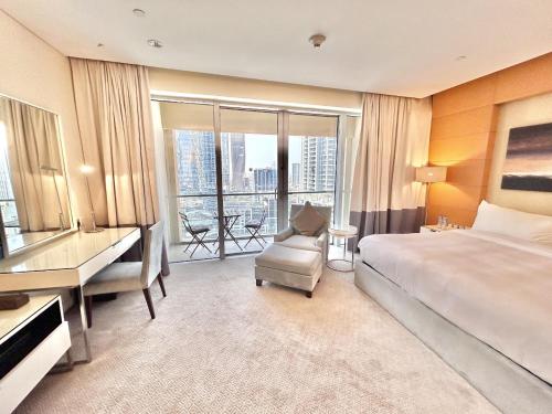 a hotel room with a bed and a desk and a window at Fashion Avenue Dubai Mall Residences - Studio with balcony in Dubai