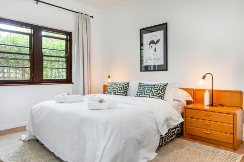 a white bedroom with a large white bed and a window at Constantia Oasis Petite in Cape Town