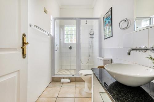 a bathroom with a shower and a sink and a toilet at Constantia Oasis Petite in Cape Town