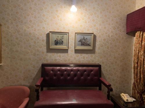 a leather bench in a room with two pictures on the wall at Kishan Palace-A heritage Hotel in Bikaner