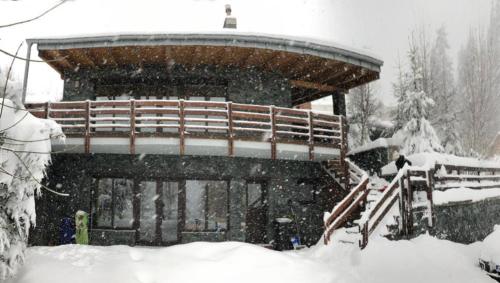 a snow covered building with a wooden bench in the snow at Bazalt Wellness Villa in Harghita-Băi
