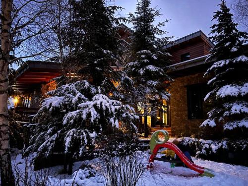 a snow covered yard with a red slide in front of a house at Bazalt Wellness Villa in Harghita-Băi