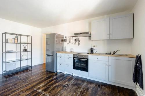 a kitchen with white cabinets and a wooden floor at L'appartement Casquette in Liège