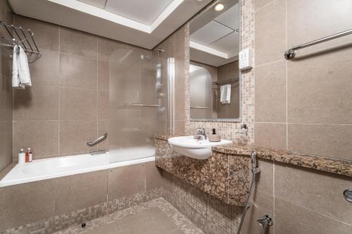 a bathroom with a sink and a tub and a toilet at Nasma Luxury Stays - Elegant 1BR With Stunning View of Park Avenue in Dubai