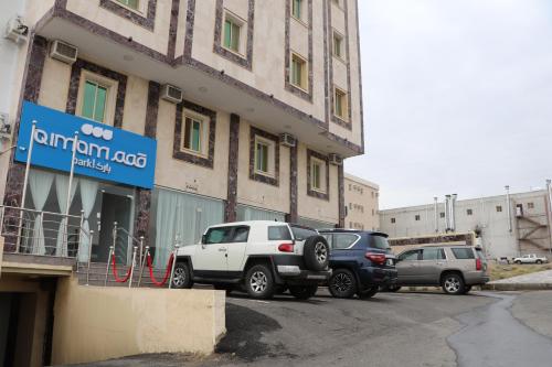 eine Gruppe von Autos, die außerhalb eines Gebäudes geparkt werden in der Unterkunft قمم بارك Qimam Park Hotel 4 in Abha