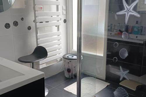 a bathroom with a shower with a black chair and a stool at Au calme de la Poterie in Châteaubriant