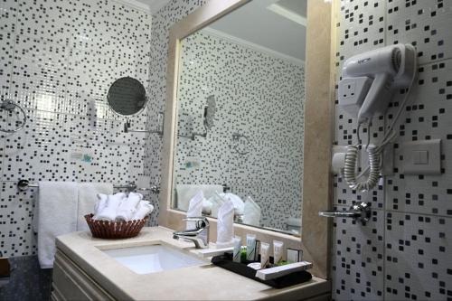 a bathroom with a sink and a shower with a phone at One Inn Hotel in Al Madinah