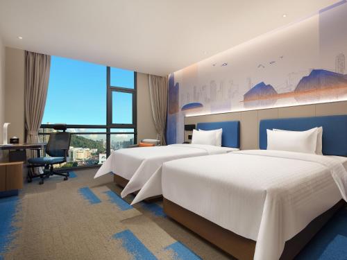 深セン市にあるHampton by Hilton Shenzhen Bao'an Airportのベッド2台とデスクが備わるホテルルームです。