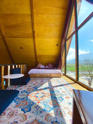 een kamer met een bed en een groot raam bij Cabin Linggayoni dieng in Diyeng