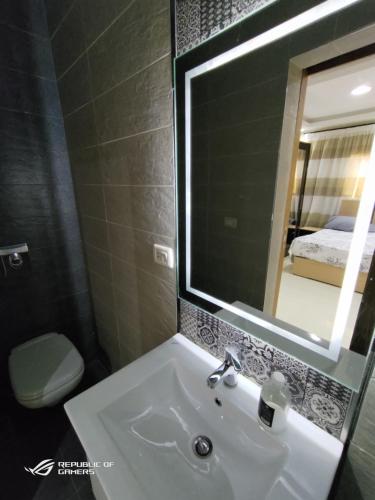 La salle de bains est pourvue d'un lavabo, d'un miroir et de toilettes. dans l'établissement 3 Bedrooms Luxurious Appartment in Nasr City, au Caire