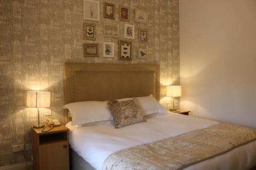 a bedroom with a bed with two lamps and pictures on the wall at Bartley Lodge Hotel in Lyndhurst
