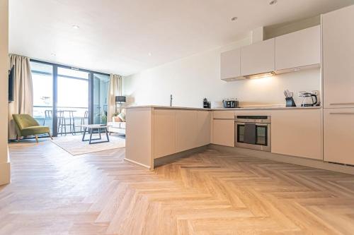 a kitchen with white cabinets and a wooden floor at 1BR Apt - Balcony - River View in Liverpool