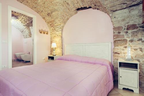 um quarto com uma cama rosa e uma parede de pedra em Blu Bosa em Bosa