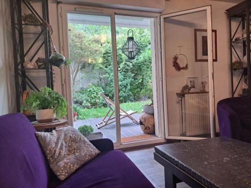 ein Wohnzimmer mit einem lila Sofa und einer Glasschiebetür in der Unterkunft Appartement cosy avec jardin et parking in Gennevilliers