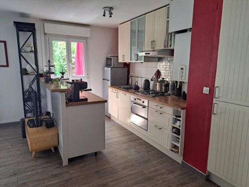 eine Küche mit weißen Schränken und einer roten Wand in der Unterkunft Appartement cosy avec jardin et parking in Gennevilliers
