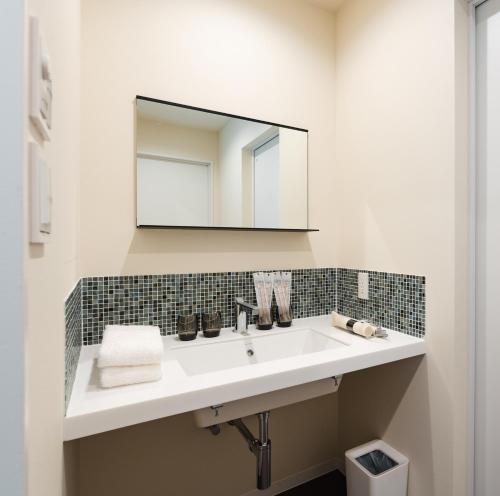 a bathroom with a white sink and a mirror at 郷音 ～G.O.A.T～ in Tsuru 