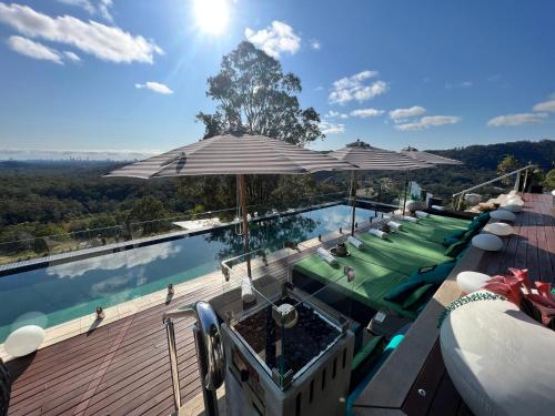 a swimming pool with umbrellas and green lounge chairs at On Eagle Wings Mountain Retreat & Spa in Neranwood