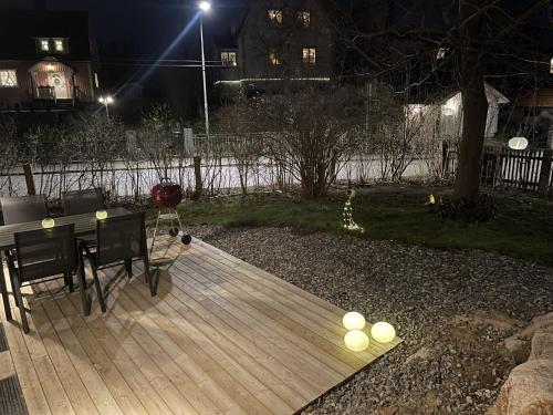 a wooden deck with a table and chairs at night at Minihus i Enskede-Årsta-Vantörs in Stockholm