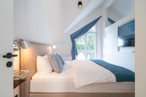 een witte slaapkamer met een bed en een raam bij Apartment Blausand in Ahrenshoop